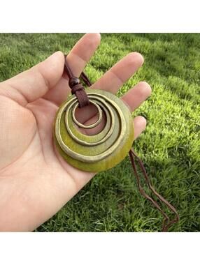 Green necklace wooden pendant with concentric circles and brown cord